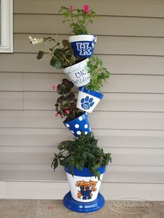 a tall blue and white planter with flowers in it's bottom tier on the side of a house