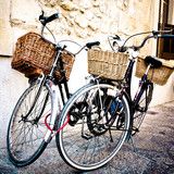 two bicycles parked next to each other on the side of a building with wicker baskets