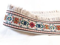 a close up of a ribbon on a white surface with flowers and hearts in the center