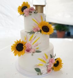 a three tiered cake with sunflowers and flowers on it