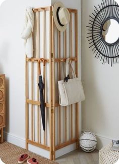 a wooden rack with umbrellas and hats hanging on it's sides next to a white wall