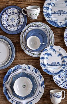 blue and white china is laid out on a wooden table with cups, saucers, and plates