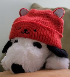 a stuffed animal with a red hat on it's head sitting on a couch