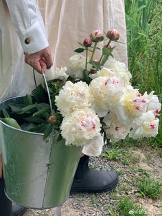 a person holding a bucket with flowers in it