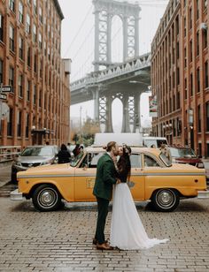 a bride and groom standing in front of a yellow taxi with the brooklyn bridge in the background