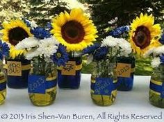 sunflowers and daisies are in mason jars on a table with blue ribbon