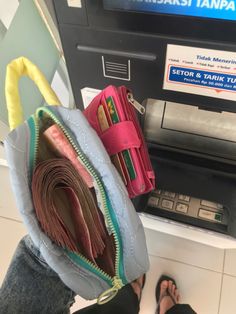 a person standing next to an atm machine with their wallets in front of them