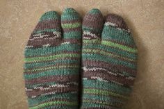 a pair of green and brown striped mittens sitting on top of a tile floor