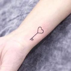 a small key tattoo on the wrist is shown in black ink, with a heart at the end