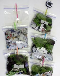 four bags filled with green leafy vegetables on top of a white table next to a cell phone