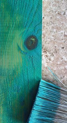 a blue brush sitting on top of a wooden floor next to a piece of wood