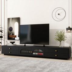 a large flat screen tv sitting on top of a black entertainment center in a living room