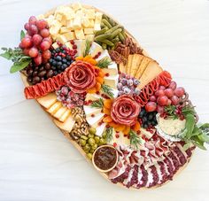 a platter filled with different types of cheeses and fruit on top of a white table