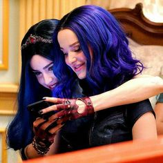 two women with purple hair looking at a cell phone