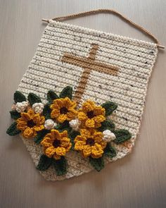 a crocheted bag with flowers and a cross on it