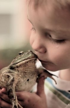 a young boy is kissing a frog on the nose in black and whit photo