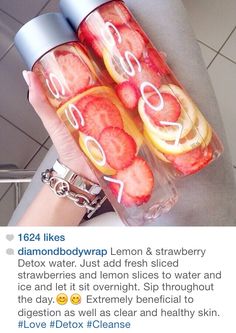 a person holding two water bottles filled with fruit