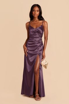 a woman in a long purple dress with her legs slited up and holding a bouquet