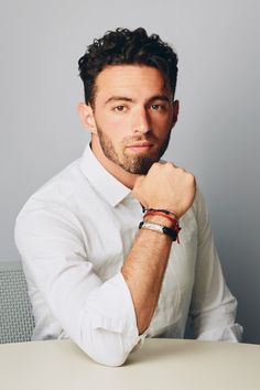 a man sitting at a table with his hand on his chin and wearing a watch