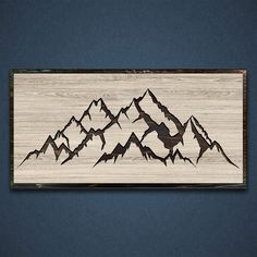 a wooden plaque with mountains carved into it