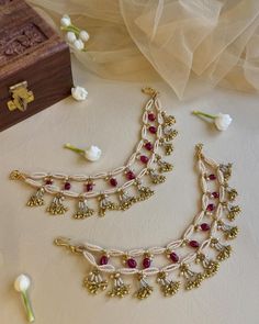 two necklaces are laying on a table next to some flowers and a wooden box