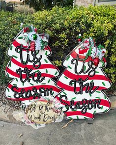 two decorated christmas trees sitting on top of a sidewalk