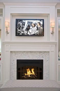 a fire place in a living room with two pictures on the wall above it and another fireplace