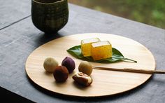 chopsticks and some food on a wooden plate next to a potted plant