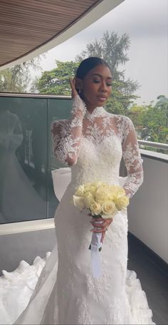 a woman in a white wedding dress holding a bouquet of flowers and posing for the camera