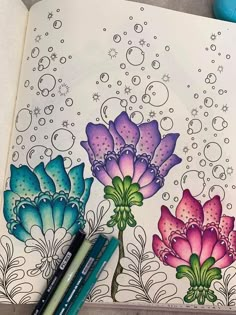 an open notebook with flowers and bubbles on the pages, along with two markers for coloring