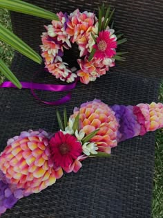 flowers are arranged on the ground next to each other with purple ribbons and bows around them