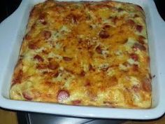 a square casserole dish with cheese and sausage on it sitting on a stove