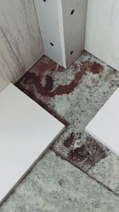 two white toilets sitting next to each other in a room with dirt on the floor