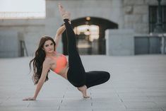 a woman in an orange top is doing a yoga pose on the ground with her legs spread out