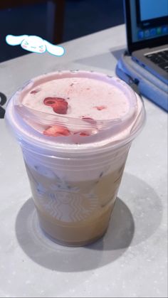 a plastic cup sitting on top of a table next to a laptop