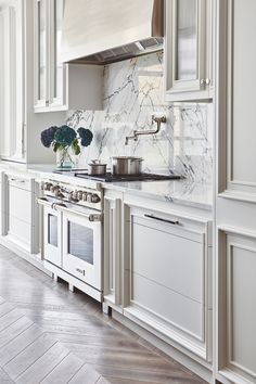 a kitchen with white cabinets and marble counter tops, along with an oven in the center