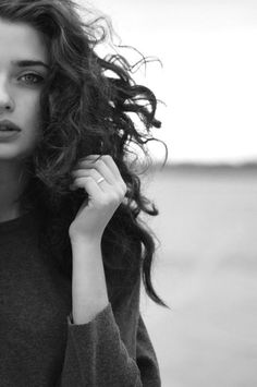 black and white photograph of a woman with long hair wearing a sweater looking at the camera