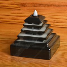 three black and white candlesticks sitting on top of each other in front of a wooden table