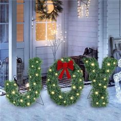 the word joy is decorated with christmas lights in front of a house and snow covered porch