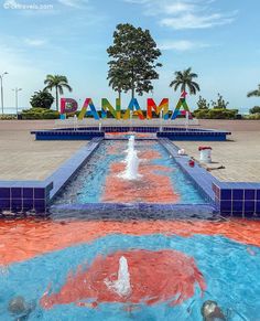 there is a colorful fountain in the center of this park with words painted on it