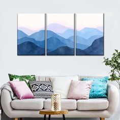 three blue mountains in the distance with pink and purple pillows on a white couch next to a coffee table