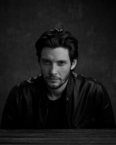 a black and white photo of a man in a leather jacket looking at the camera