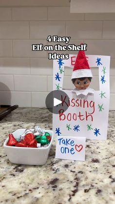 an elf is holding a sign in front of a bowl of candy