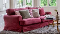 a living room with pink couches and pillows on top of the couch, next to a coffee table