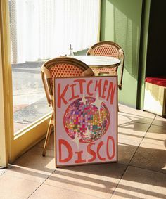 there is a sign that says kitchen disco on the sidewalk next to chairs and tables