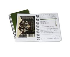 an open notebook with writing on it next to a notepad and pen in front of the book