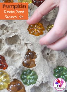 a hand reaching for some kind of jelly in the sand that is filled with different colored jelly