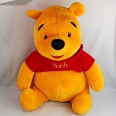 a large yellow teddy bear sitting on top of a white backdrop with the word pooh written on it