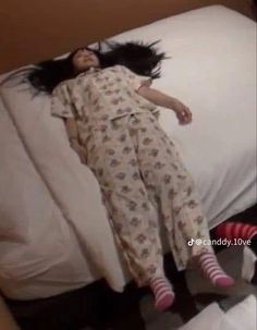 a woman laying on top of a bed next to a white pillow with her hair in the air