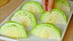 someone is cutting up cabbage on a white platter with other vegetables in the background